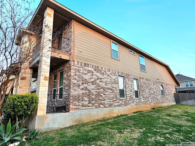 view of home's exterior with a balcony and a yard