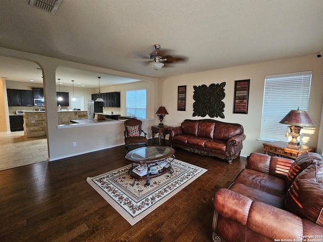 living room with a textured ceiling, dark hardwood / wood-style floors, and ceiling fan