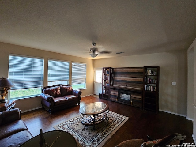 living room featuring ceiling fan, wood-type flooring, a textured ceiling, and plenty of natural light