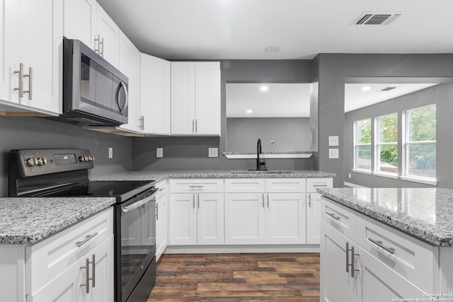 kitchen with light stone countertops, appliances with stainless steel finishes, dark hardwood / wood-style floors, and white cabinets