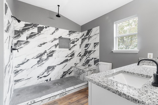 bathroom featuring toilet, vaulted ceiling, and tiled shower