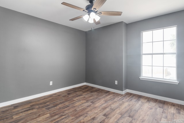 empty room with dark wood-type flooring, ceiling fan, and a wealth of natural light