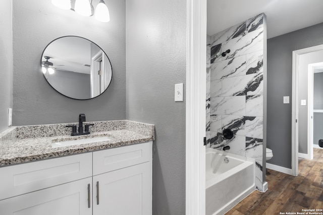 full bathroom featuring vanity, tiled shower / bath, hardwood / wood-style flooring, and toilet