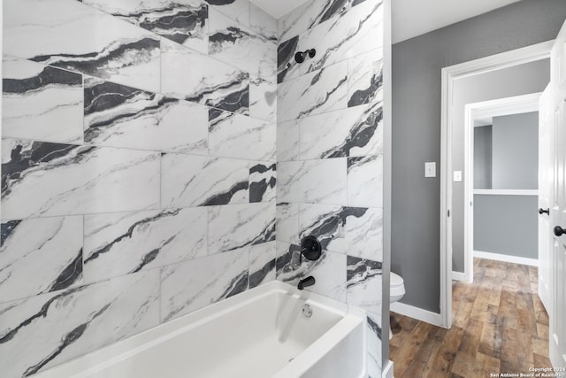 bathroom featuring tiled shower / bath combo, wood-type flooring, and toilet