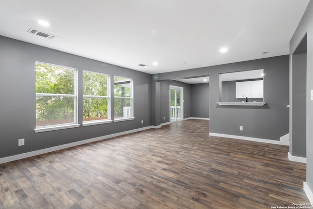 unfurnished living room featuring a wealth of natural light and dark hardwood / wood-style floors