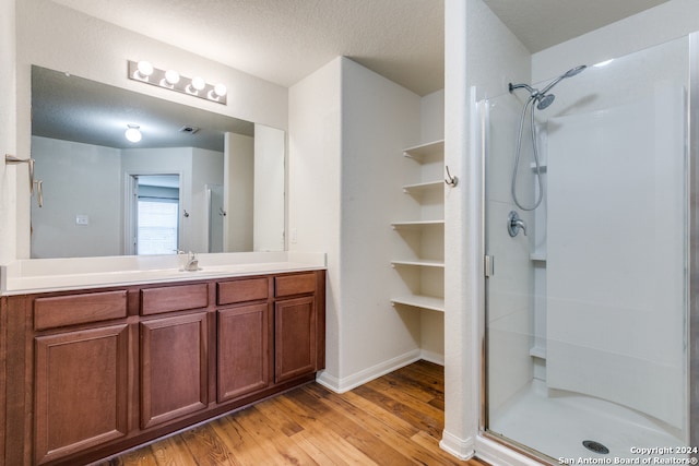 bathroom featuring a shower with door, a textured ceiling, hardwood / wood-style flooring, and vanity