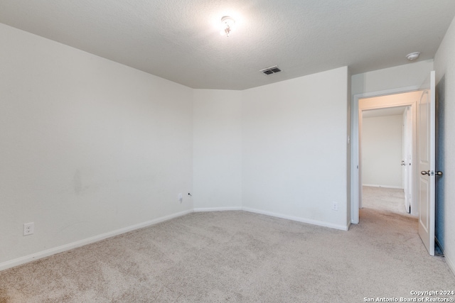 spare room with light carpet and a textured ceiling