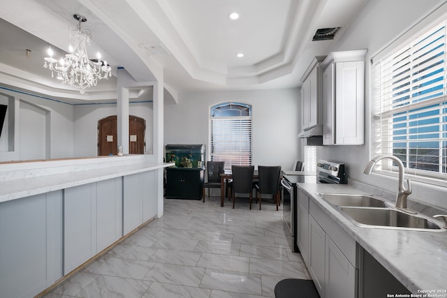 kitchen featuring a tray ceiling, sink, a wealth of natural light, and stainless steel range with electric cooktop