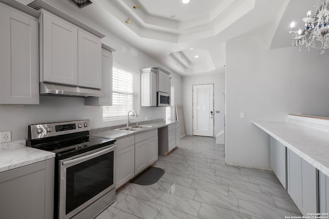 kitchen featuring appliances with stainless steel finishes, a tray ceiling, sink, gray cabinets, and decorative light fixtures