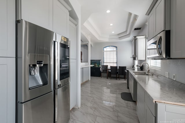 kitchen featuring sink, stainless steel appliances, and a tray ceiling