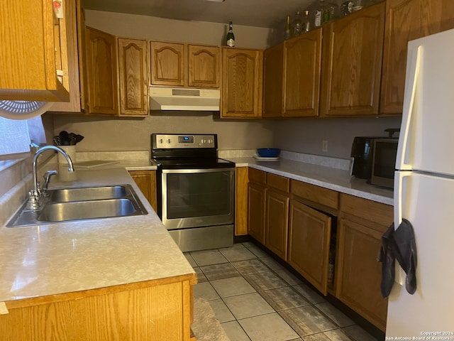 kitchen with stainless steel electric stove, light tile patterned floors, sink, and white refrigerator