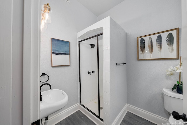 bathroom featuring sink, hardwood / wood-style floors, a shower with shower door, and toilet