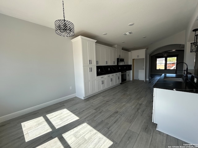 kitchen featuring sink, stainless steel appliances, hanging light fixtures, light hardwood / wood-style flooring, and white cabinets