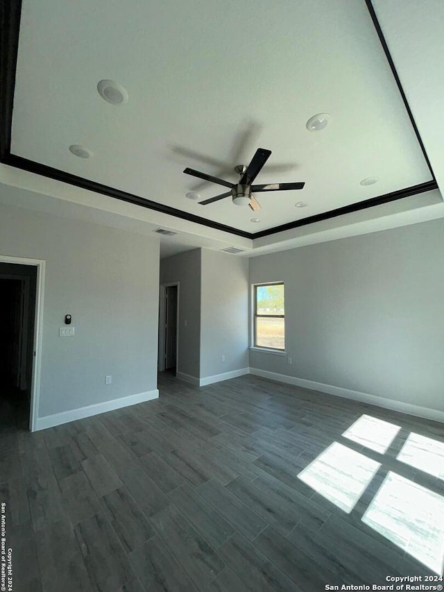 unfurnished room featuring hardwood / wood-style floors, ceiling fan, and a raised ceiling