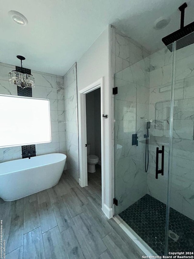 bathroom with toilet, hardwood / wood-style floors, an inviting chandelier, and independent shower and bath