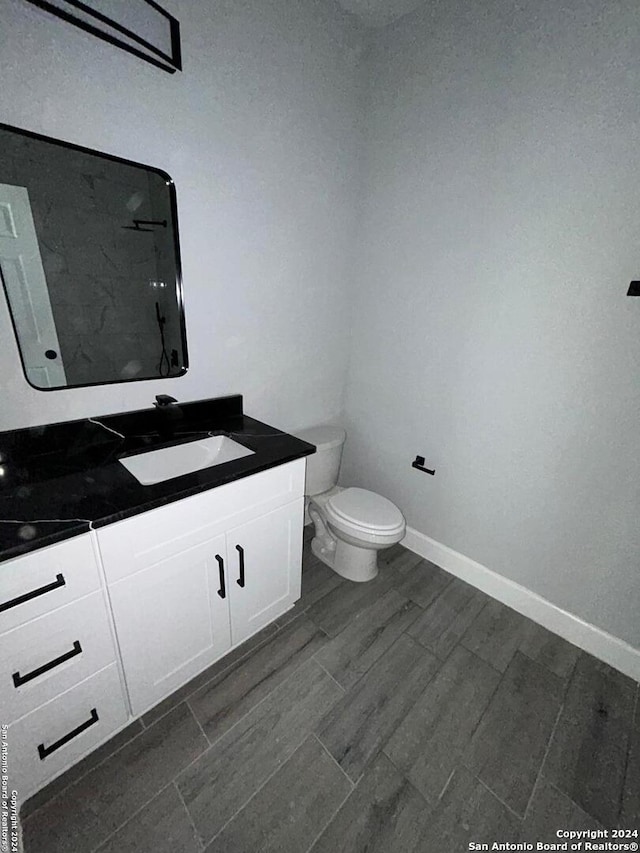 bathroom with hardwood / wood-style floors, vanity, and toilet