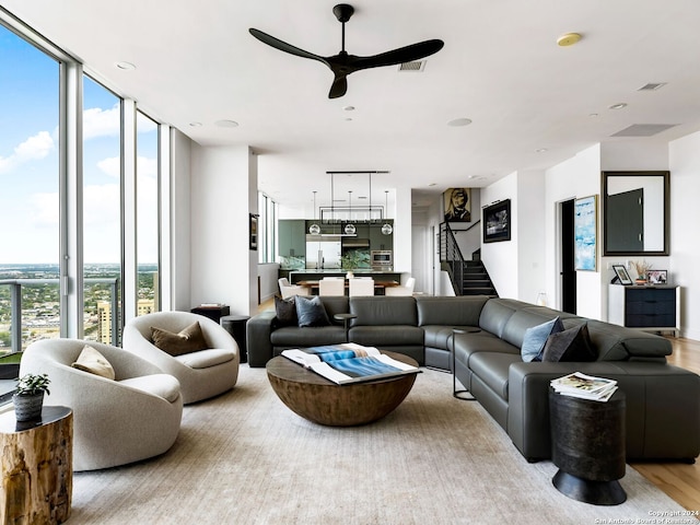 living room with light hardwood / wood-style floors, a wall of windows, and ceiling fan