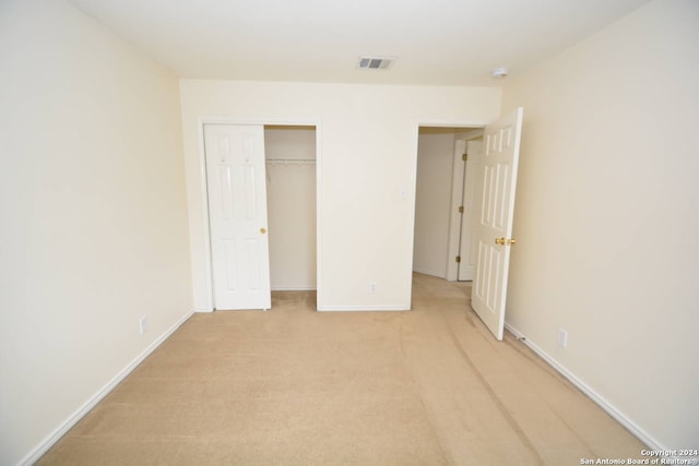 unfurnished bedroom featuring a closet and light colored carpet