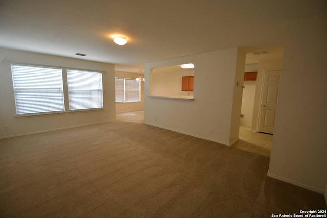 empty room featuring carpet flooring and an inviting chandelier