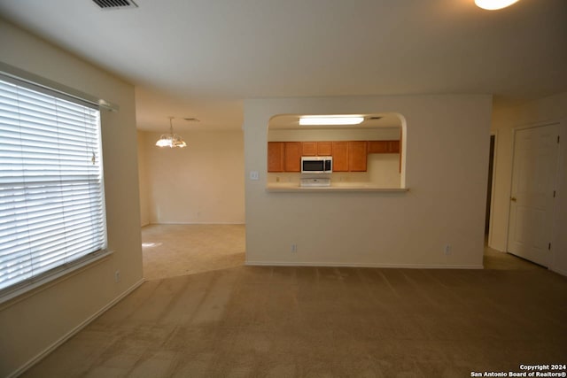 unfurnished living room featuring light carpet and an inviting chandelier