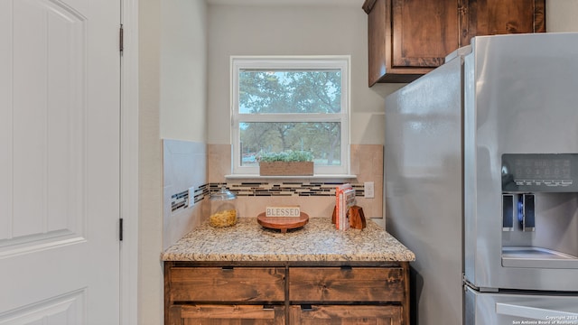 kitchen featuring light stone counters and stainless steel fridge with ice dispenser