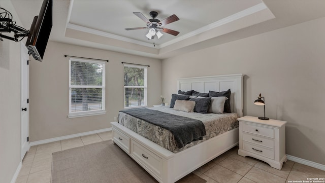 bedroom with ornamental molding, a tray ceiling, light tile patterned floors, and ceiling fan