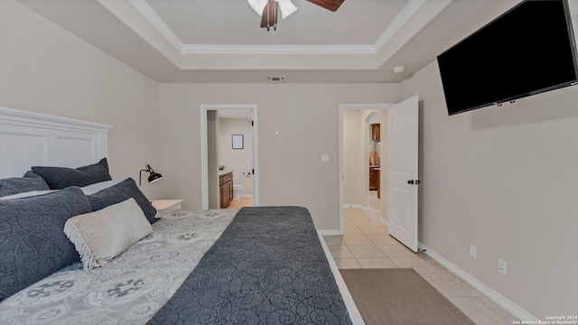 bedroom featuring crown molding, ensuite bathroom, a tray ceiling, and ceiling fan