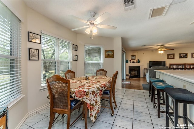 tiled dining area with a textured ceiling and ceiling fan