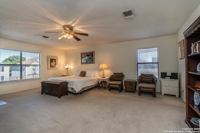 carpeted bedroom featuring a textured ceiling, multiple windows, and ceiling fan