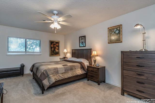 bedroom featuring ceiling fan, a textured ceiling, and light colored carpet