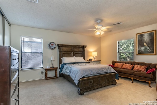 bedroom featuring light carpet, a textured ceiling, multiple windows, and ceiling fan