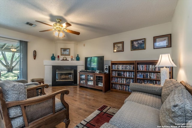 living room featuring a textured ceiling, wood-type flooring, and ceiling fan