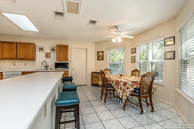 tiled dining area featuring sink, a textured ceiling, and ceiling fan