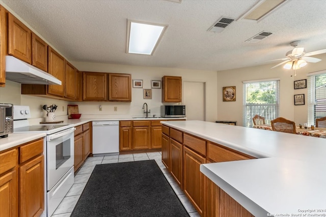 kitchen featuring sink, light tile patterned floors, a textured ceiling, white appliances, and ceiling fan