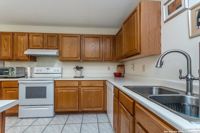 kitchen with sink, a textured ceiling, white appliances, and light tile patterned floors