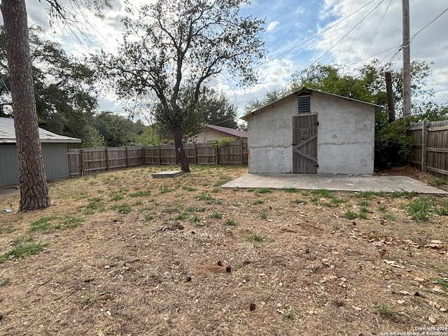 view of yard featuring a fenced backyard, an outdoor structure, and a storage shed