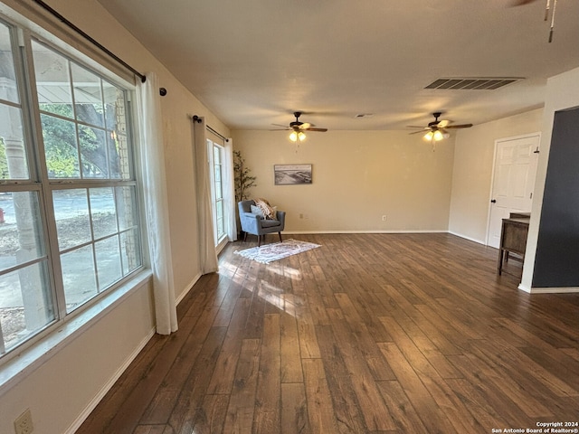 unfurnished living room with a ceiling fan, baseboards, visible vents, and dark wood-type flooring