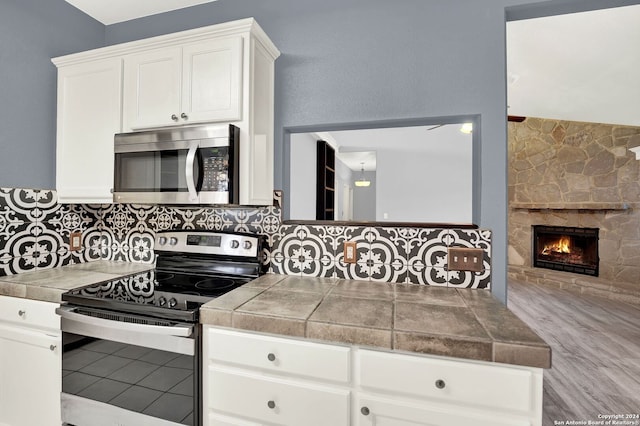 kitchen with tile countertops, white cabinets, and stainless steel appliances