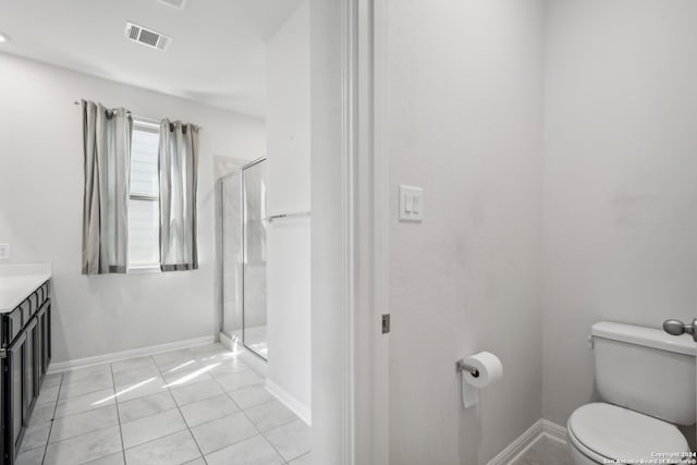 bathroom with toilet, a shower with shower door, vanity, and tile patterned floors