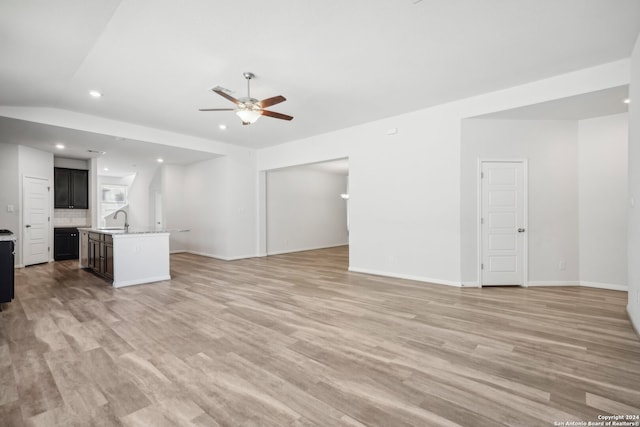 unfurnished living room featuring light hardwood / wood-style flooring, sink, vaulted ceiling, and ceiling fan