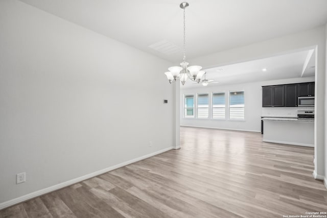 unfurnished dining area with light hardwood / wood-style floors and ceiling fan with notable chandelier