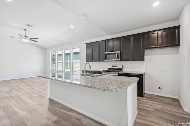 kitchen featuring tasteful backsplash, appliances with stainless steel finishes, sink, an island with sink, and lofted ceiling