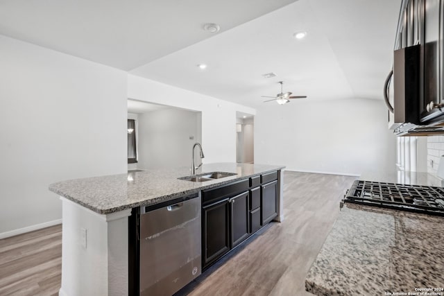 kitchen with light stone counters, stainless steel appliances, sink, and a kitchen island with sink