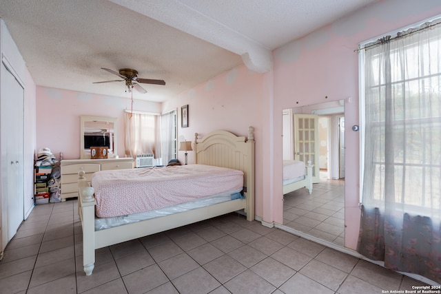 bedroom with a closet, a textured ceiling, light tile patterned floors, and ceiling fan