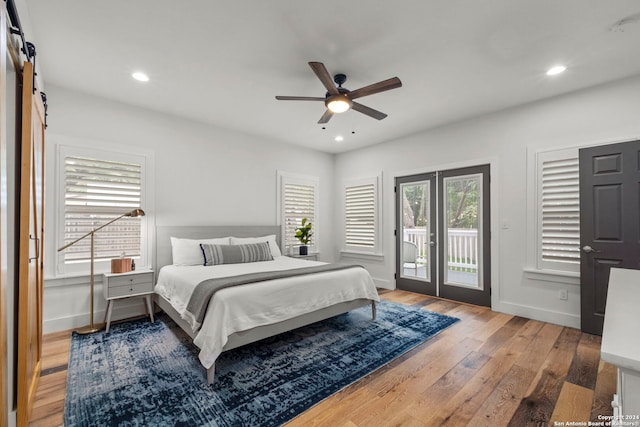 bedroom featuring hardwood / wood-style flooring, access to outside, a barn door, and ceiling fan