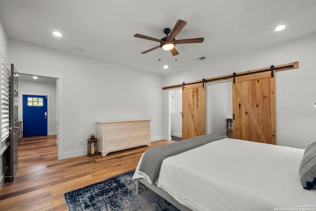 bedroom featuring wood-type flooring, ceiling fan, and a barn door