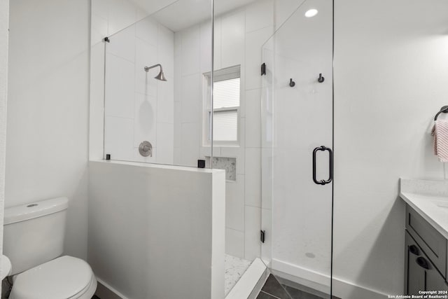 bathroom with a shower with door, vanity, toilet, and tile patterned flooring