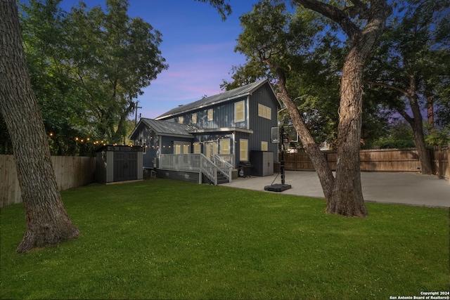 back house at dusk featuring a patio and a yard