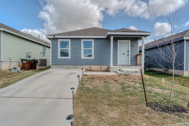 bungalow-style house featuring a front lawn and central air condition unit