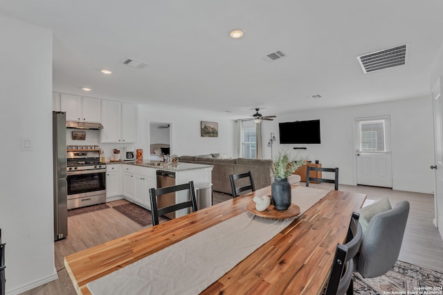 dining area featuring ceiling fan, sink, and light wood-type flooring